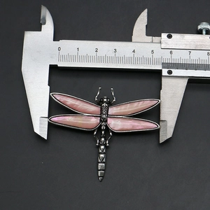 Macro detail of vintage dragonfly brooch showing 5.5cm width measurement on scale