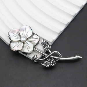 Macro detail of a vintage flower brooch featuring iridescent black shell petals and pearl