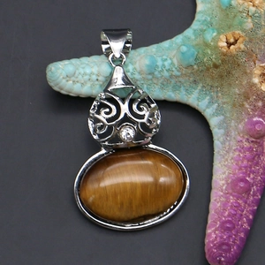 Macro shot of tiger eye stone pendant with silver filigree and clear zircon detail