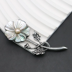 Macro detail of elegant black shell flower brooch with pearl center on silver stem