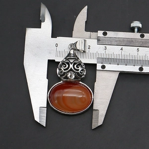 Macro view of gourd-shaped carnelian pendant measurement with a digital caliper