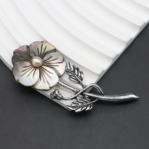Detail showing the iridescent black shell petals and pink pearl on the flower brooch