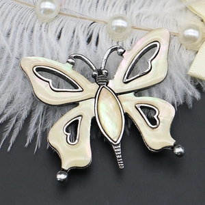 Macro detail of butterfly brooch showing iridescent abalone shell inlay and silver heart cutouts