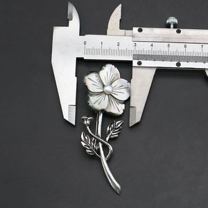 Detailed dimension measurement of natural shell flower brooch with caliper tool