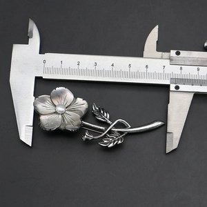 Detailed measurement of a shell flower brooch with a vernier caliper showing its 7.5cm length