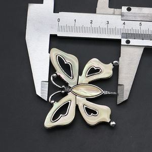 Macro view of butterfly brooch pendant measuring 3.8cm with iridescent shell inlay