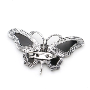 Natural abalone shell butterfly brooch with secure metal pin back on white background