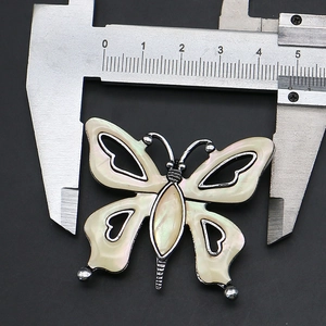 Macro shot showing 45mm width of butterfly pendant with shell inlay on dark background