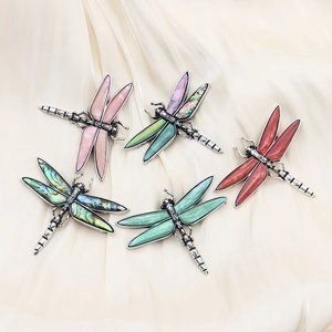 Vintage dragonfly brooches with colorful abalone shells on silk background