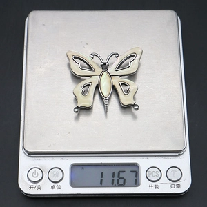 Macro shot of butterfly brooch on digital scale weighing 11.67 grams for jewelry DIY