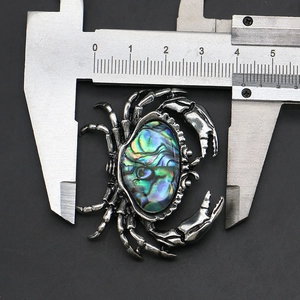Macro shot of crab brooch featuring colorful abalone shell inlay and vintage alloy texture
