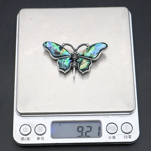Macro shot of butterfly shell pendant on a digital scale showing weight of 9.21 grams