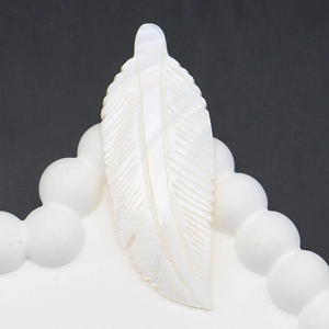 Macro view of white mother of pearl feather pendant showing detailed shell carvings