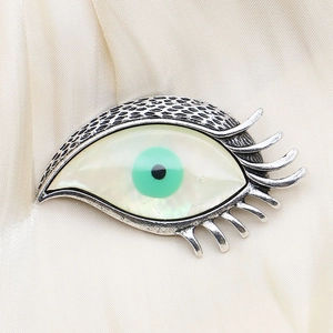 Broche œil vintage avec nacre irisée et iris vert sur un tissu en soie de couleur champagne