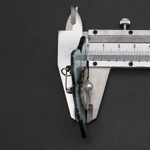 Detail view of shell flower brooch thickness measured with caliper showing 7mm depth