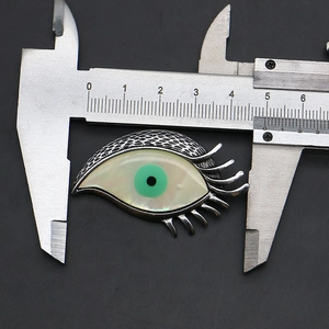 Vue macro d'une broche oeil en argent avec nacre mesurée par un pied à coulisse