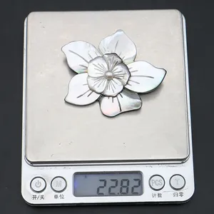 Macro view of shell flower brooch on scale showing 22.82g weight and pearl center
