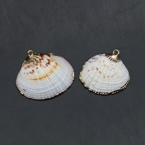 Détail de pendentifs en coquillage naturel avec bords dorés et anneaux de suspension