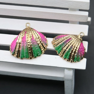 Detail of pink and green enamel scallop shell pendants with gold plated edges for DIY jewelry