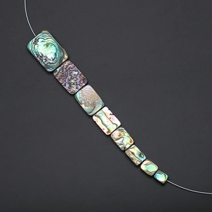 Dettaglio macro di perline rettangolari in conchiglia di abalone con riflessi iridescenti