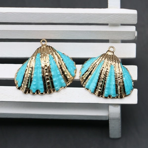 Detailed view of turquoise blue scallop pendants with golden edges for DIY jewelry making