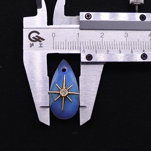 Macro view showing natural stone water drop pendant dimensions with a caliper tool