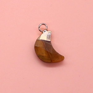 Macro detail of crescent moon tiger eye stone pendant with rose gold plated clasp