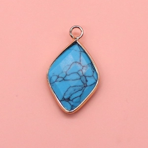 Detailed macro shot of a diamond-shaped turquoise pendant with gold-plated metal edging