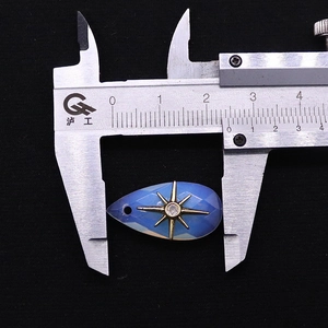 Detailed measurement of blue teardrop gemstone pendant with gold star inlay using calipers
