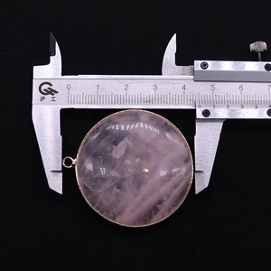 Macro view of a 44mm round pink quartz pendant with gold trim being measured by a caliper