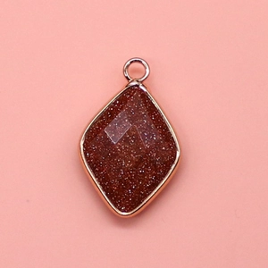 Macro detail of diamond-shaped goldstone pendant with elegant rose gold plating
