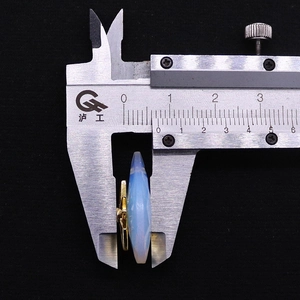 Measuring 8.5mm thickness of blue opal stone pendant with golden star inlay using caliper