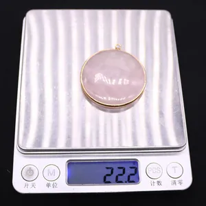 Vue détaillée d'un pendentif en cristal rose sur balance affichant un poids de 22,2 g