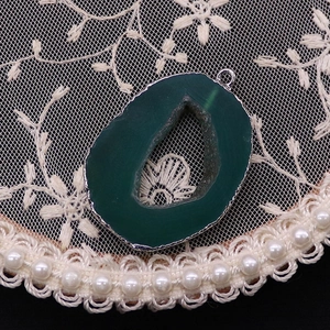 Macro detail of natural green agate geode pendant with silver plated metallic edging