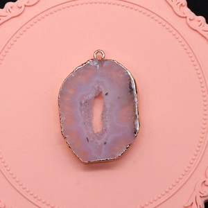 Macro-opname van lichtroze druzy geode agaat hanger met vergulde randen en oogje