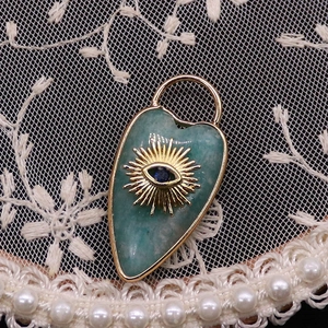 Detailed close-up of a heart-shaped turquoise stone pendant with golden evil eye sunburst