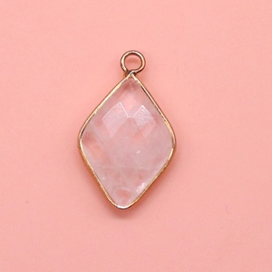 Macro detail of diamond-shaped pink quartz pendant with gold plated metal border