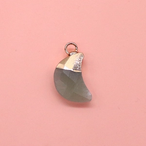 Macro detail of moon shaped grey faceted stone pendant with golden plated metal cap