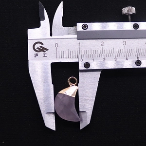 Macro shot showing measurement of a faceted pink stone moon pendant with rose gold bail