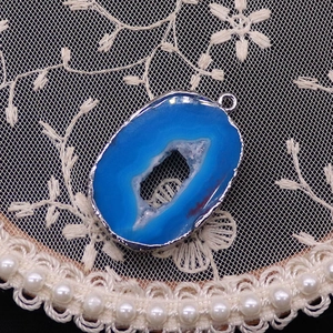 Detail showing blue agate geode pendant with silver electroplated edges and crystal core