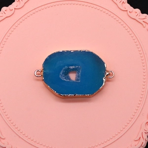 Dettaglio del connettore in agata blu naturale con bordi dorati e doppi anelli per gioielli