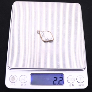 Detailed view of 2.2g diamond-shaped natural stone pendant being weighed on a scale