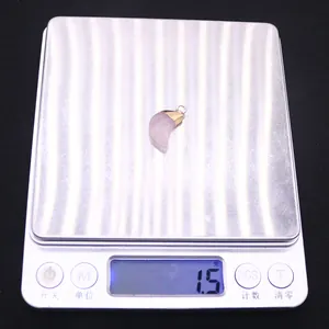 Macro shot of a pink natural stone moon pendant on a digital scale weighing 1.5 grams