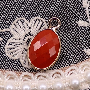 Macro detail of oval faceted red gemstone pendant with gold plated edge on lace background