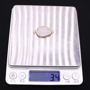Pink oval gemstone connector in gold frame on digital scale showing weight of 3.4g