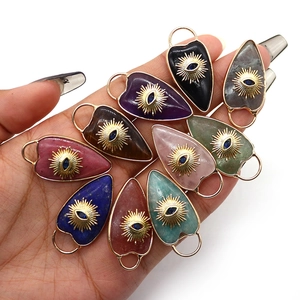 Natural heart stone pendants with golden evil eye sun motifs held in a hand display