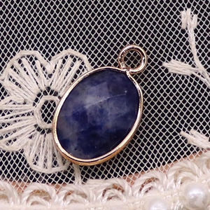 Macro view of oval faceted lapis lazuli pendant with rose gold plated metal on lace