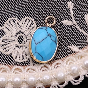 Detail of oval turquoise pendant with golden metal frame and black textures