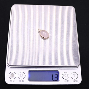 Detailed view of an oval pink quartz pendant with gold plating on a digital scale weighing 1.3g