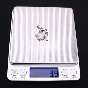 Macro detail of whale pendant weight measurement showing 3.9 grams on digital scale